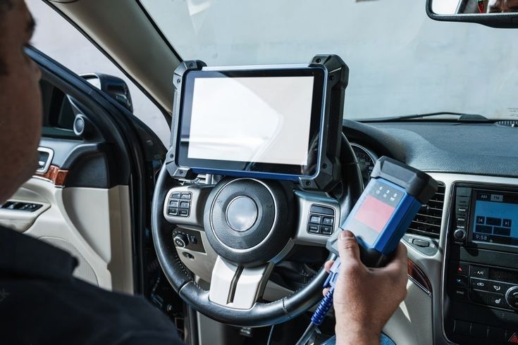 Mobile locksmith technician using a key programming device inside a car in Harare