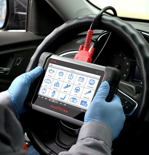 Mobile locksmith technician using a key programming device inside a car in Harare