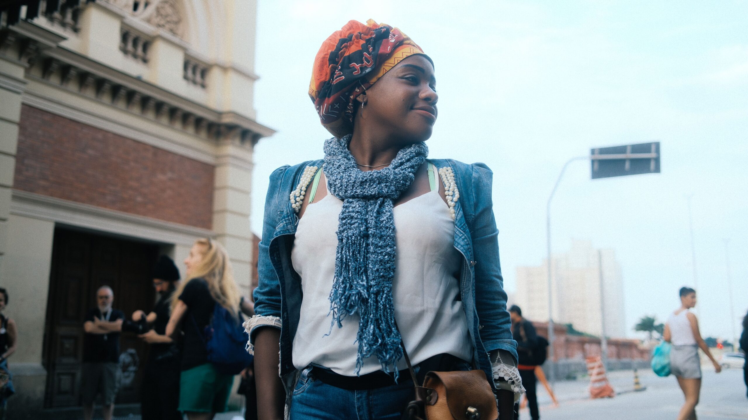 A fashionable young woman stands confidently on a vibrant city street.